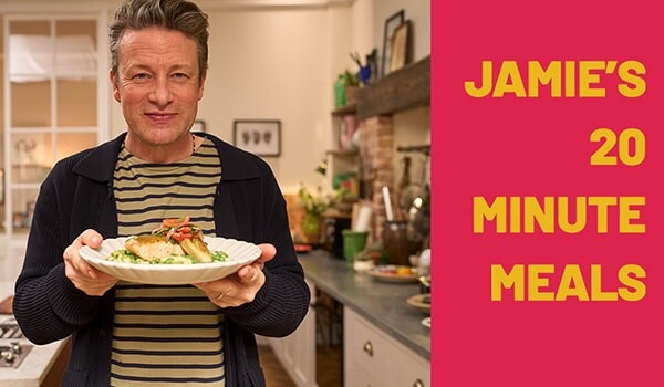 Mann hält Teller mit Essen in einer modernen Küche, Werbung für Jamie’s 20-Minuten-Mahlzeiten.